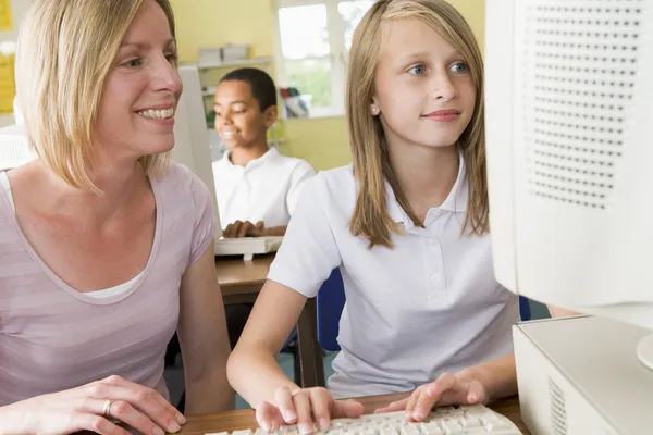Lärare och skolflicka studera framför en skola dator — Stockfoto