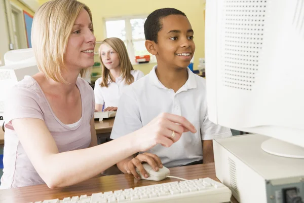 Teacher and schoolgirl studying in front of a school computer — Stock Photo, Image