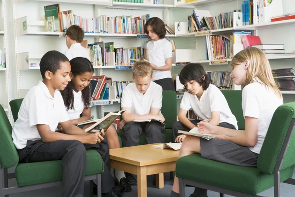 Junior school studenter arbetar i ett bibliotek — Stockfoto