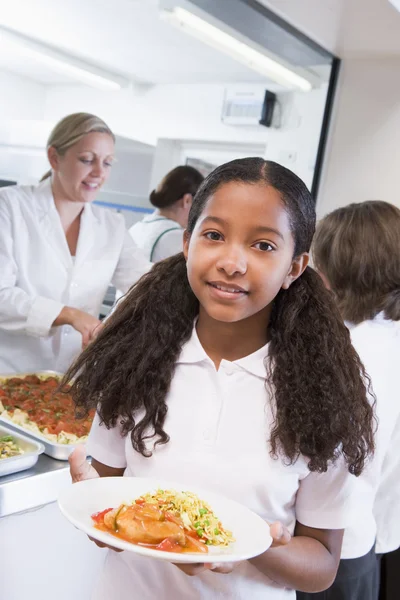 Schoolgirl holding plate of lunch in school cafeteria — Stock Photo, Image