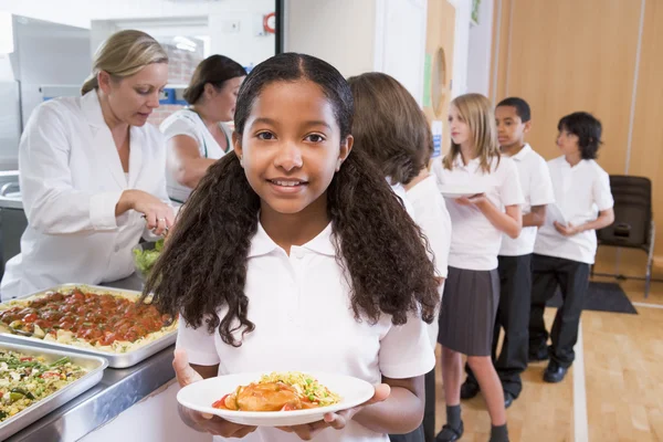 Skolflicka håller plattan av lunch i skolmatsalen — Stockfoto