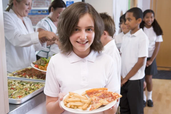เด็กนักเรียนถือจานอาหารกลางวันในโรงอาหารของโรงเรียน — ภาพถ่ายสต็อก