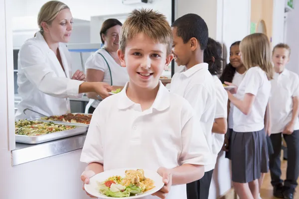 学童在学校餐厅里拿着一盘午餐 — 图库照片