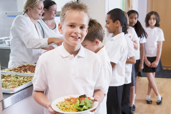 Skolpojke som håller tallrik med lunch i skolmatsalen — Stockfoto
