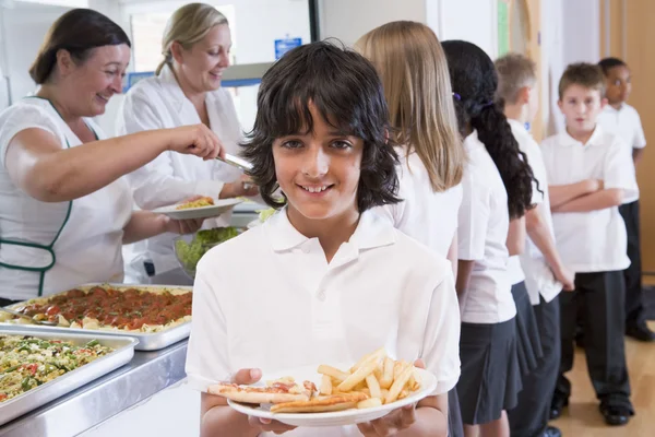 Школьник держит тарелку с обедом в школьной столовой — стоковое фото