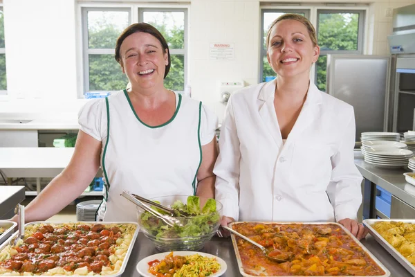 Yemekhanedeki tepsilerin yanında yemek servisi yapan kadınlar. — Stok fotoğraf