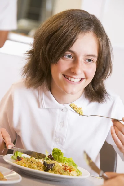 Skolflicka njuter av sin lunch i en skolmatsal — Stockfoto