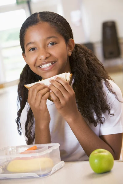 Iskoláslány élvezi az ebédjét az iskolai menzán. — Stock Fotó