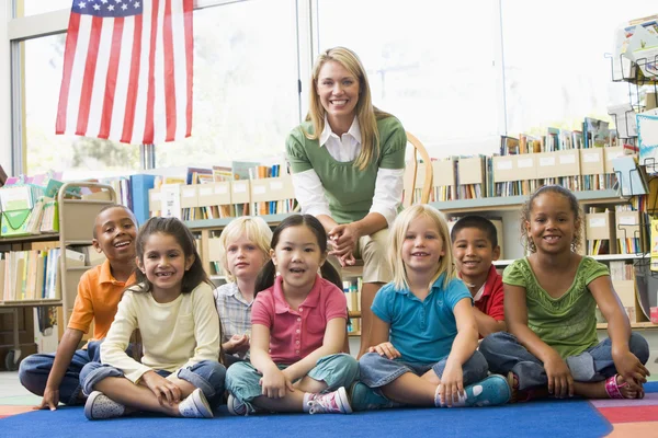 図書館で子供たちと座っている幼稚園の先生 — ストック写真