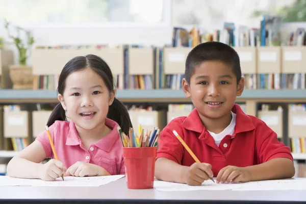 Crianças do jardim de infância sentadas na mesa e escrevendo em sala de aula — Fotografia de Stock