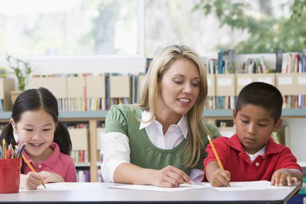 Kindergärtnerin Hilft Schülern Beim Schreiben — Stockfoto