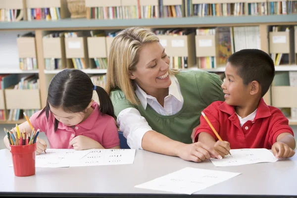 Kindergärtnerin hilft Schülern beim Schreiben — Stockfoto