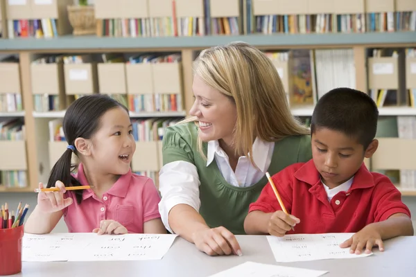 Kindergärtnerin hilft Schülern beim Schreiben — Stockfoto
