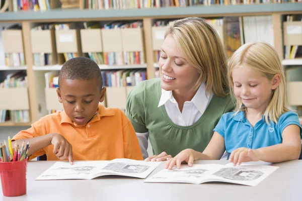 Преподаватель детского сада помогает учащимся с навыками чтения — стоковое фото