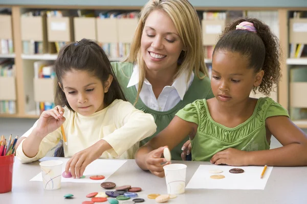 Kindergarten teacher sitting with students in art class, — Stock Photo, Image