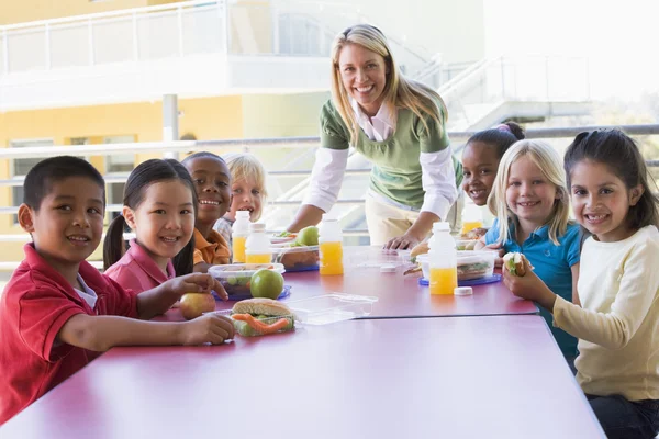 Νηπιαγωγός Επιβλέποντας Παιδιά Που Τρώνε Μεσημεριανό Γεύμα — Φωτογραφία Αρχείου