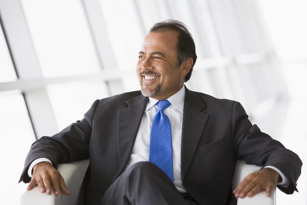 Businessman sitting in chair in lobby — Stock Photo, Image