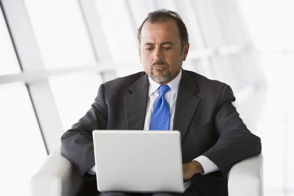 Üzletember, hallban laptop dolgozik — Stock Fotó