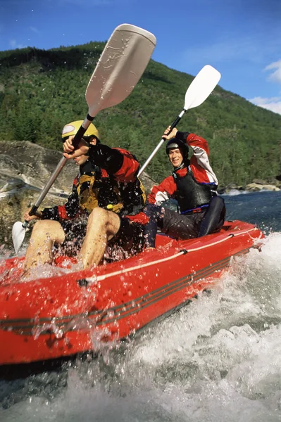 Two paddling inflatable boat down rapids Stock Image