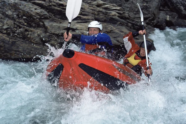 Two paddling inflatable boat down rapids Stock Picture