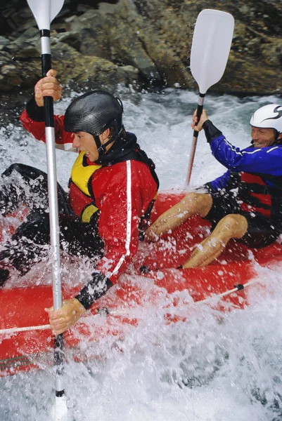 Two paddling inflatable boat down rapids Stock Photo