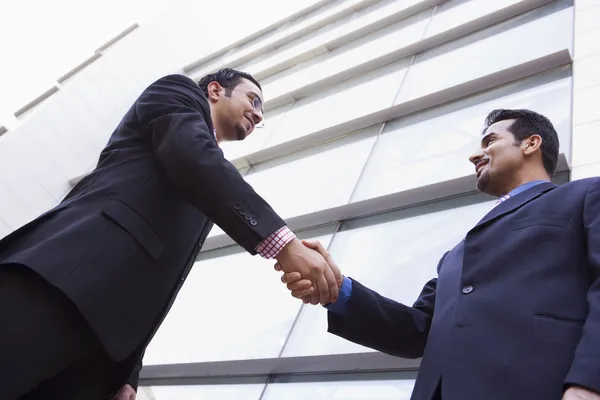 两个商人在办公楼外握手 免版税图库照片