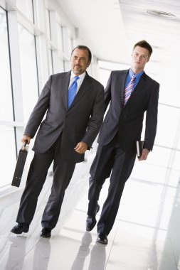 Two businessmen walking through lobby clipart