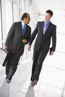 Businessmen walking through office lobby clipart