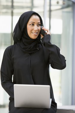 A Middle Eastern business woman sitting with a laptop clipart