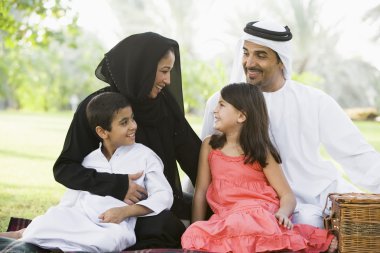 A Middle Eastern family sitting in a park clipart