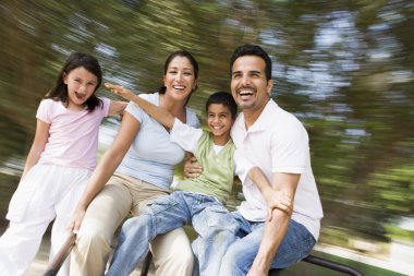 Family having fun on spinning roundabout clipart