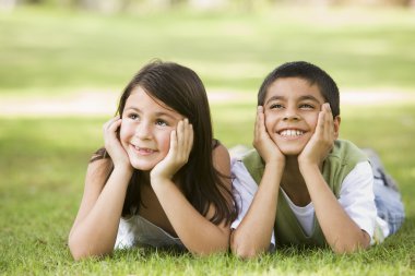 Two children relaxing in park together clipart