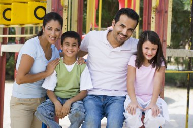 Family having fun in playground on climbing frame clipart