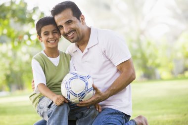 Father and son playing football clipart