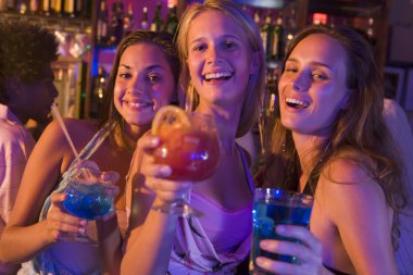 Three young women with drinks in a nightclub clipart