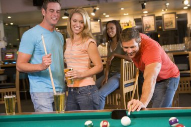 Young adults playing pool in a bar clipart