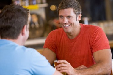 Two men talking over beer in a bar clipart