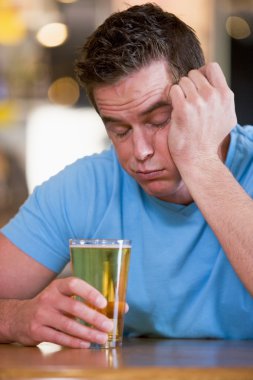 Young man with beer falling asleep at bar clipart