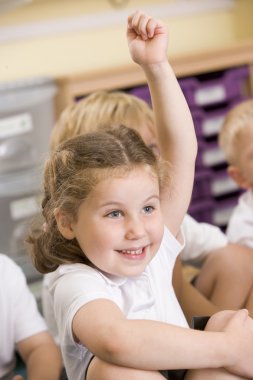 A schoolgirl raises her hand in a primary class clipart