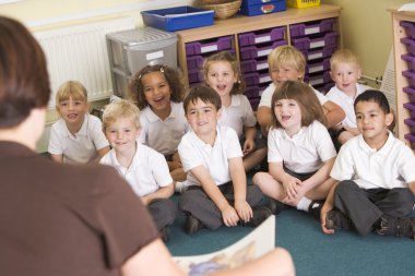 A teacher reads to schoolchildren in a primary class clipart