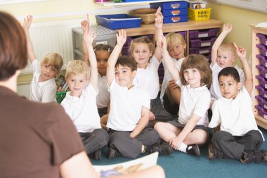 Schoolchildren raise their hand in a primary class clipart