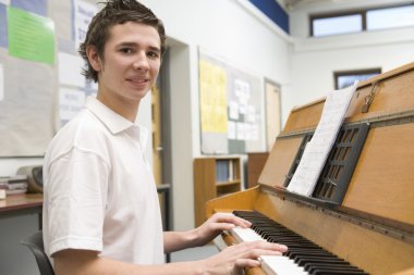 Schoolboy playing piano in music class clipart