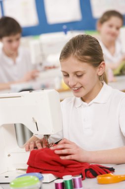 Schoolgirl using a sewing machine in sewing class clipart
