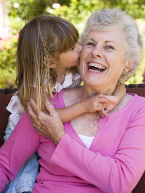 Grandmother getting a kiss from granddaughter clipart