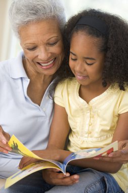 Grandmother and granddaughter reading and smiling clipart