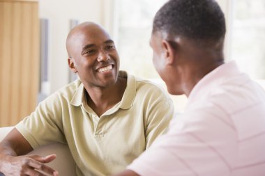 Two men in living room talking and smiling clipart