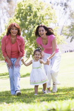 Grandmother with adult daughter and granddaughter in park clipart