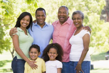 Extended family standing in park smiling clipart