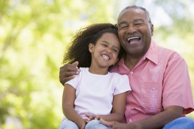 Grandfather and granddaughter outdoors smiling clipart