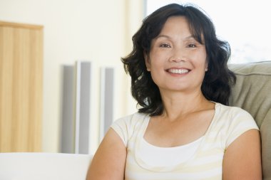 Woman sitting in living room smiling clipart